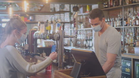 Clienta-Con-Máscara-En-El-Bar-Haciendo-Pagos-Sin-Contacto-Por-Bebidas-Durante-Una-Pandemia-De-Salud