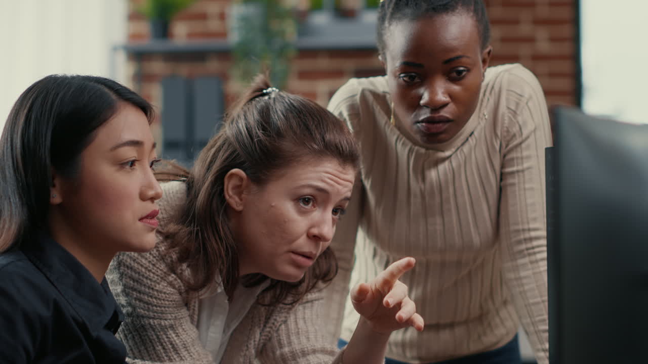 Software engineer pointing at computer screen explaining running code to coworkers brainstorming software ideas