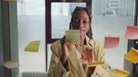 African-american-business-woman-using-sticky-notes-brainstorming-problem-solving-strategy-on-glass-whiteboard-leader-woman-Planning-Project-On-Post-It-Sticky-Notes-in-office.