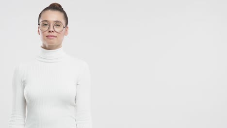 young funny girl wearing round spectacles, pointing rightwards, looking surprised and happy isolated on gray background with copy space