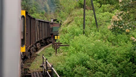 A scenic train winds its way through dense jungle and rolling hills on the famous Ella to Kandy route in Sri Lanka.