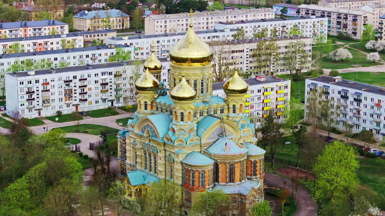Orthodox church shining domes stands near renovated Soviet apartments in Liepaja
