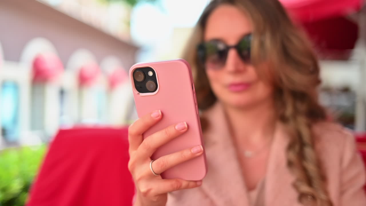 Woman working on mobile phone at a restaurant terrace, slow motion
