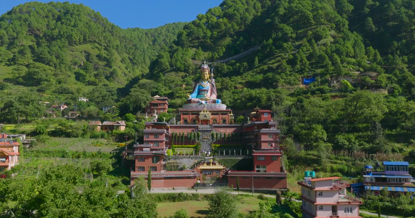 Cảnh quay drone từ bên cạnh ghi lại bức tượng Guru Rinpoche Padmasambhava khổng lồ và kiến trúc chùa Phật giáo được bao quanh bởi những ngọn đồi xanh tươi tuyệt đẹp của Pharping, Nepal