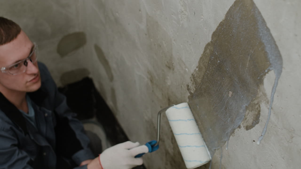 Worker Repairing a Concrete Wall with a Roller