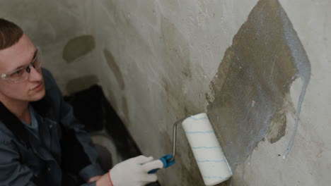 worker repairing a concrete wall with a roller