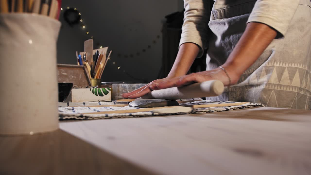 Pottery in the studio - young woman puts the clay on the table and starts kneading it