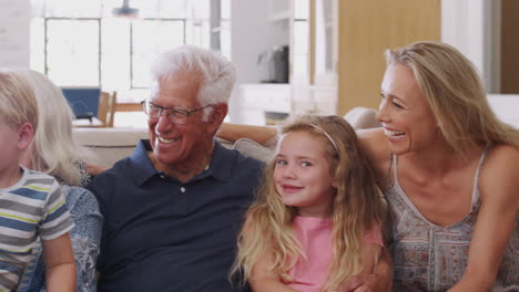 Portrait-Of-Multi-Generation-Family-Sitting-On-Sofa-At-Home