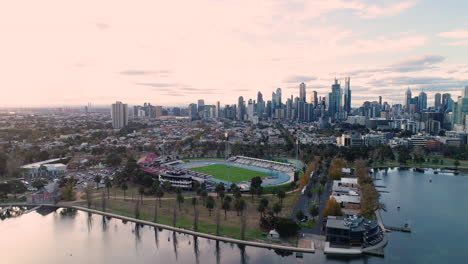 Smooth-orbit-of-Melbourne-Aquatic-Center-with-stunning-view-of-Melbourne-CBD-as-seen-from-Albert-Park-Lake,-Melbourne,-Australia