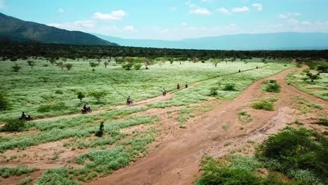 tourists riding motorcycles traveling towards lake magadi in kenya - aerial drone shot