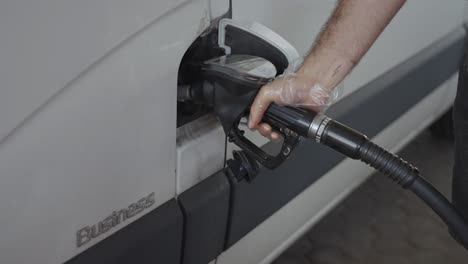 hand inserting diesel pump nozzle into a white van