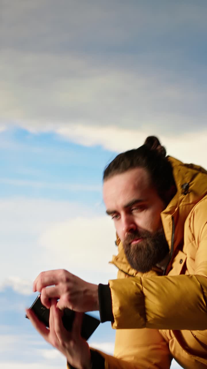 Uomo che tiene lo smartphone davanti a un cielo montano suggestivo