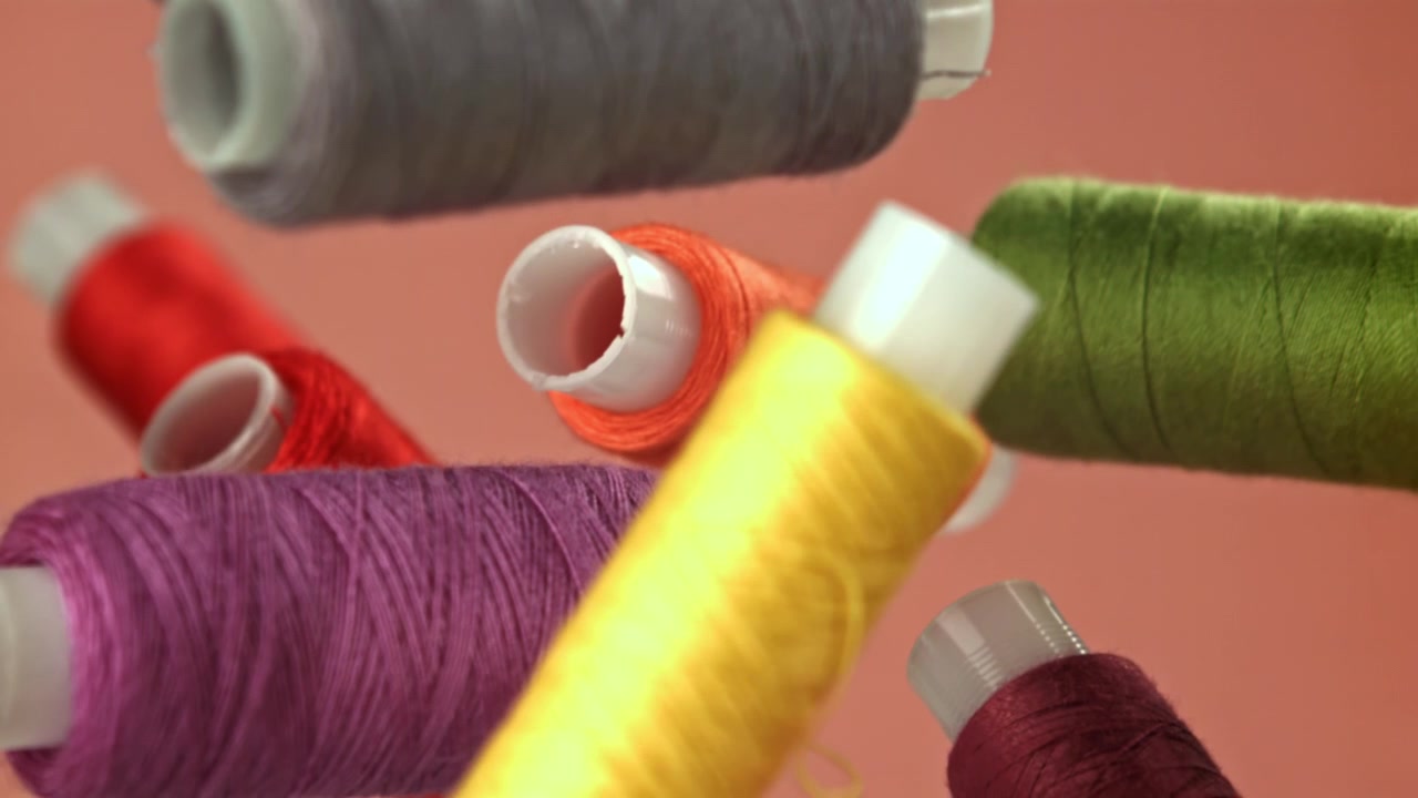 Vibrant Spools of Sewing Thread Falling in Slow Motion