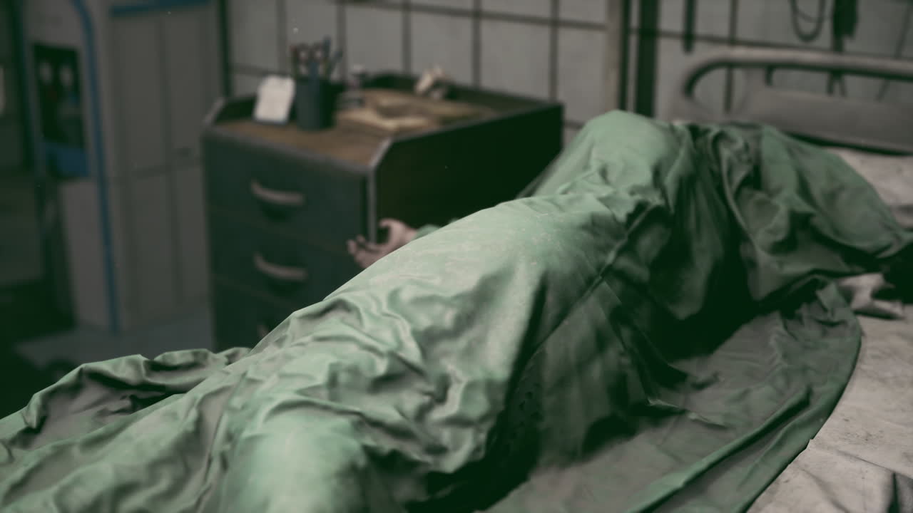 Hospital bed with a patient covered in a green blanket during evening hours