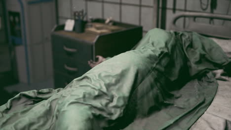 hospital bed with a patient covered in a green blanket during evening hours