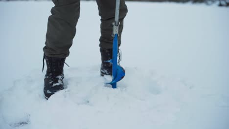 drilling a hole in a frozen river for ice fishing