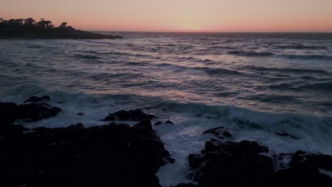 aerial shot of the rocky seashore towards the sea with large waves of water, drone tilting upward