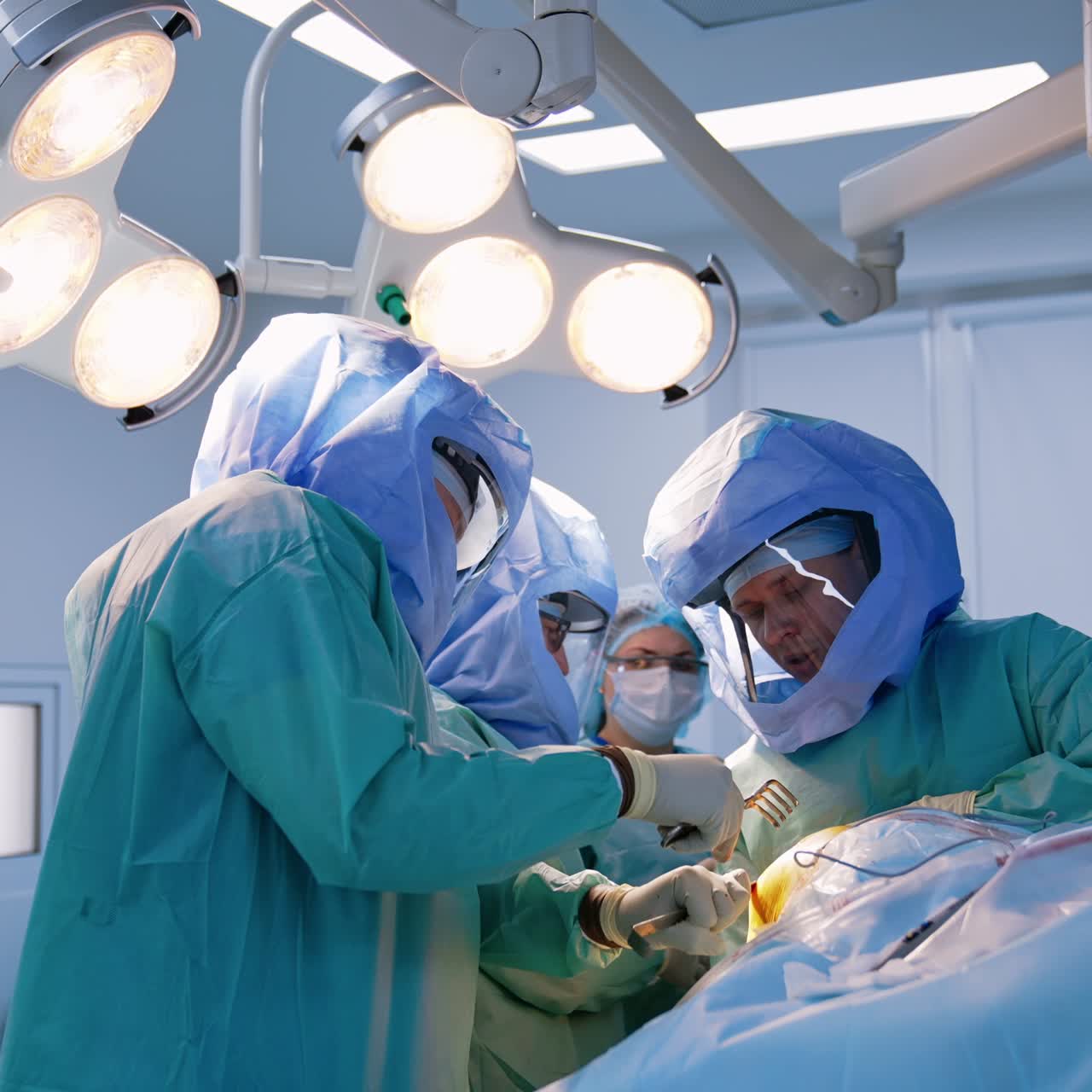 Male surgeon wearing a robe and protective helmet holding the tools in both hands. Doctors perform arthroscopy operation