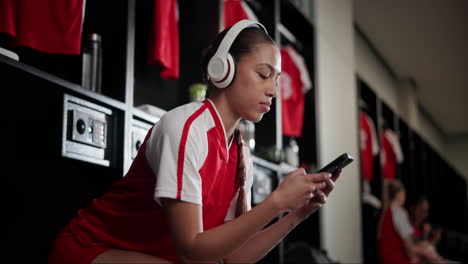 woman in locker room with headphones and phone