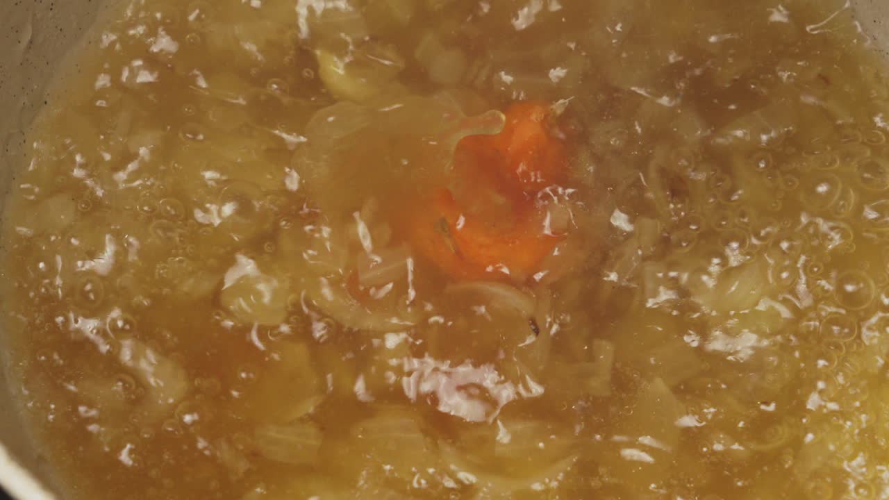 Primo piano di fette di carota fresche che cadono in una zuppa di verdure bollente. Perfetto per enfatizzare storie sull'alimentazione sana e la nutrizione.