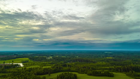 an epic aerial timelapse captures clouds moving across the sky at sunset, revealing a vast and beautiful landscape of green forests, meadows, and lakes in latvia