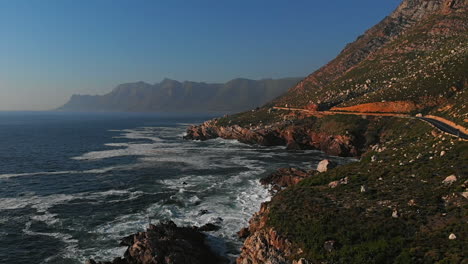 content-from-Aerial-drone-flying-low-over-nature-of-coastal-clarens-drive-Gordons-bay-with-rocks,-boulders,-sea,-ocean-cliffs-and-crashing-white-wash-waves