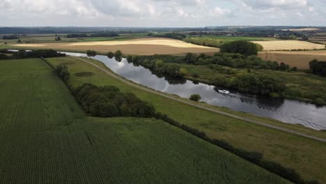 the nottinghamshire countryside drone footage crosses the river trent as a river boat sails along on a sunny, summers day