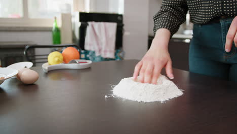 hands of a woman preparing flour for dressing with chicken eggs