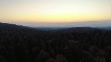 Clip-Aéreo-De-Un-Bosque-En-La-Zona-De-Los-Alpes-Bávaros,-Con-Una-Cámara-Inclinada-Para-Revelar-El-Panorama-De-Las-Montañas,-Durante-Las-Horas-Del-Amanecer