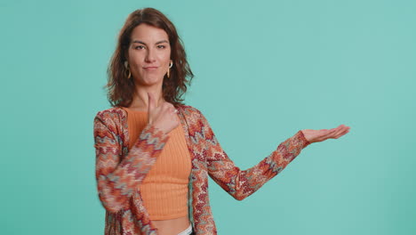 mujer joven mostrando los pulgares hacia arriba y señalando a la izquierda en el espacio en blanco lugar para su logotipo de publicidad