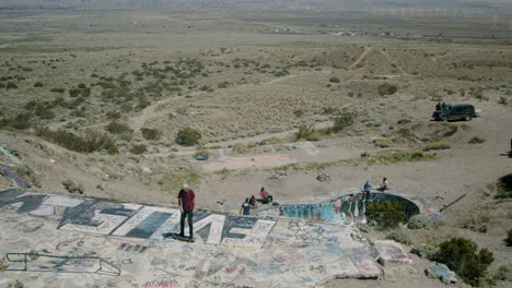 skateboarding and graffiti at an abandoned desert structure with a view of wind turbines
