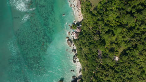 Top-down-aerial-view-of-luxury-tropical-villas-on-Bali-coastline.-Overhead-view-of-seaside-villas-and-vacation-homes-by-turquoise-blue-sea-in-Bali