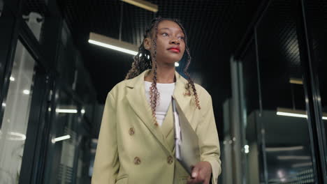 portrait of a black business woman walking down the corridor of a business center smiling