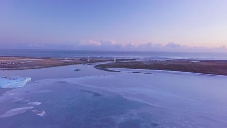 Glacial-Lagoon-Sunset-aerial-flight-over-ice-sheet-with-view-to-beach-Winter-Iceland