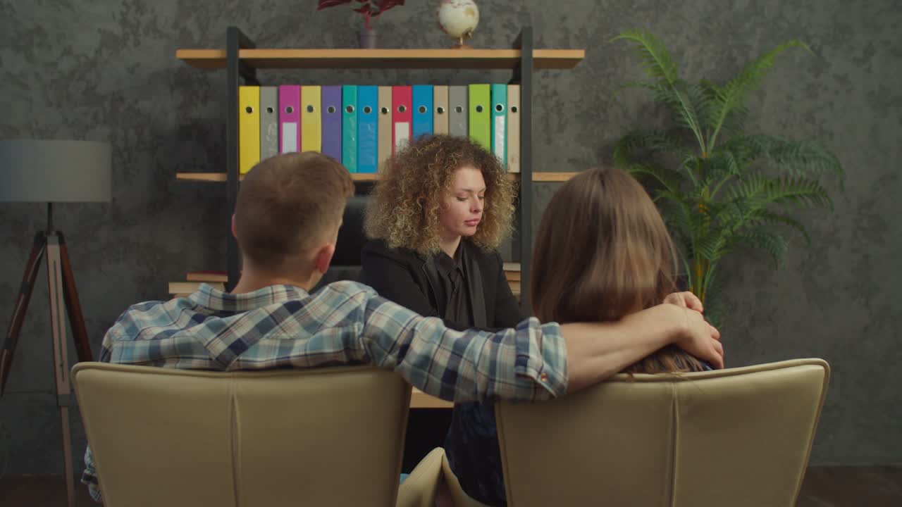 una mujer encantadora, agente inmobiliario, discutiendo un contrato inmobiliario con una pareja feliz en la oficina.