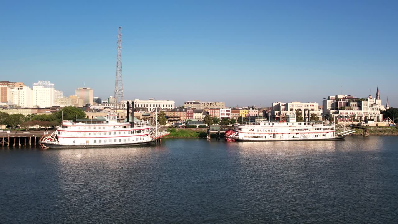 A drone flies over anchored steamboats along New Orleans' Mississippi River shoreline