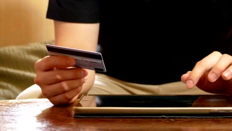 dolly shot: hombre con la mano sosteniendo una tarjeta de crédito y usando una tableta digital para comprar en línea - concepto de negocio