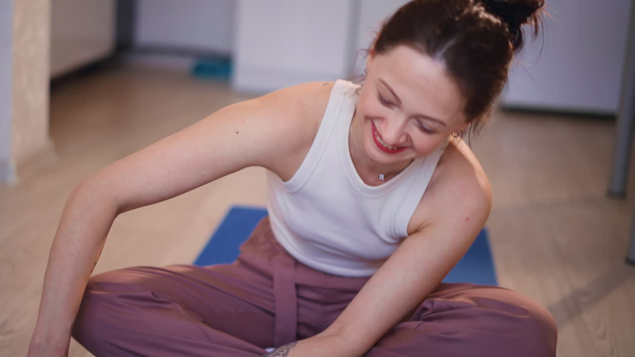White Woman Smiling While Stretching Beside Mat, Casual Home Setting With Cat, Laughter And Gentle Mobility In Relaxed Wellness Session Highlighting Joyful Movement And Connection