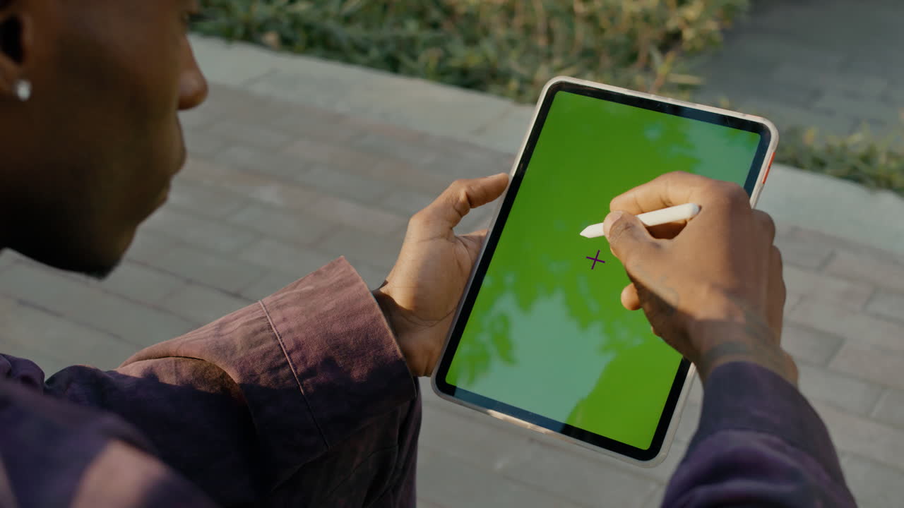 Man using a tablet with a stylus outdoors