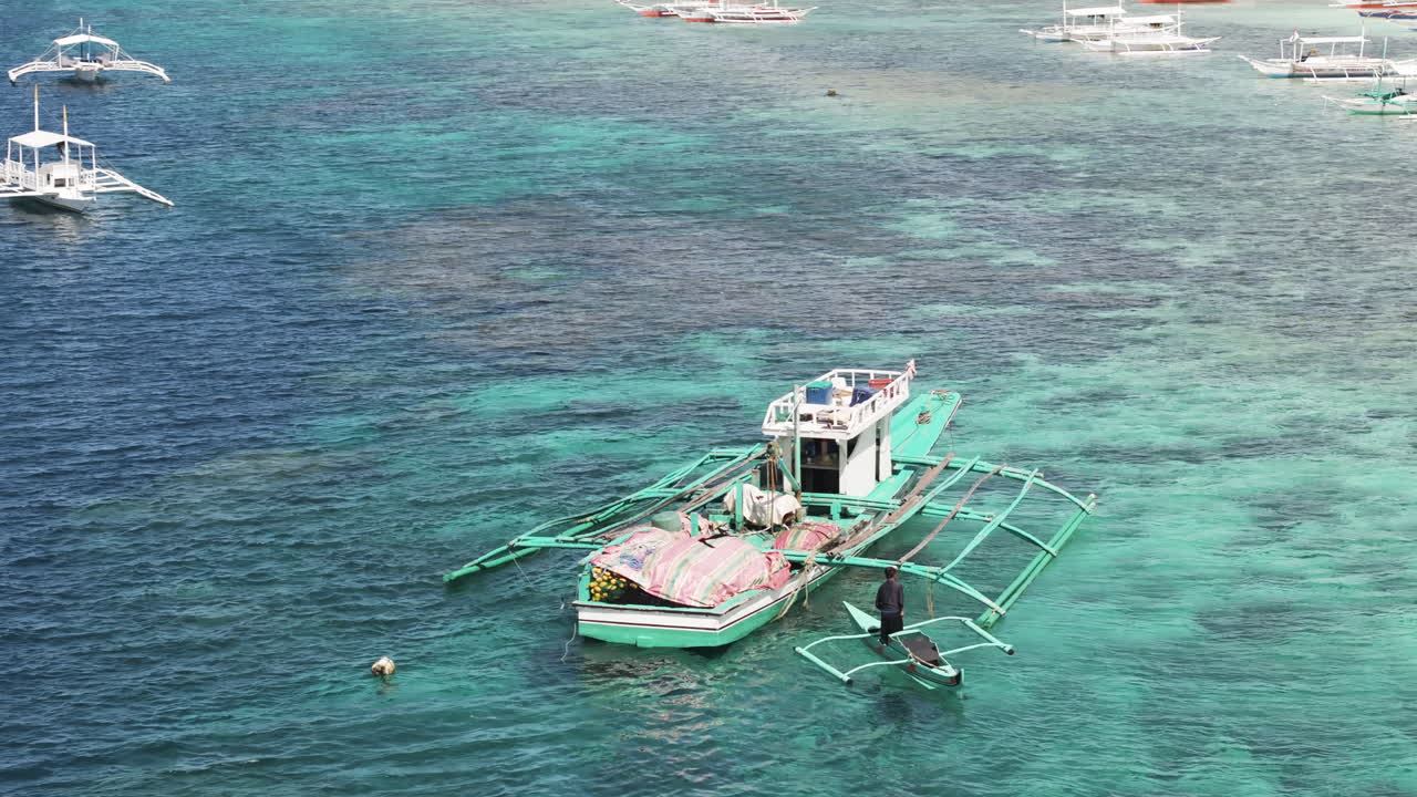 Tropical outrigger boats float on clear turquoise waters near Moalboal, Philippines
