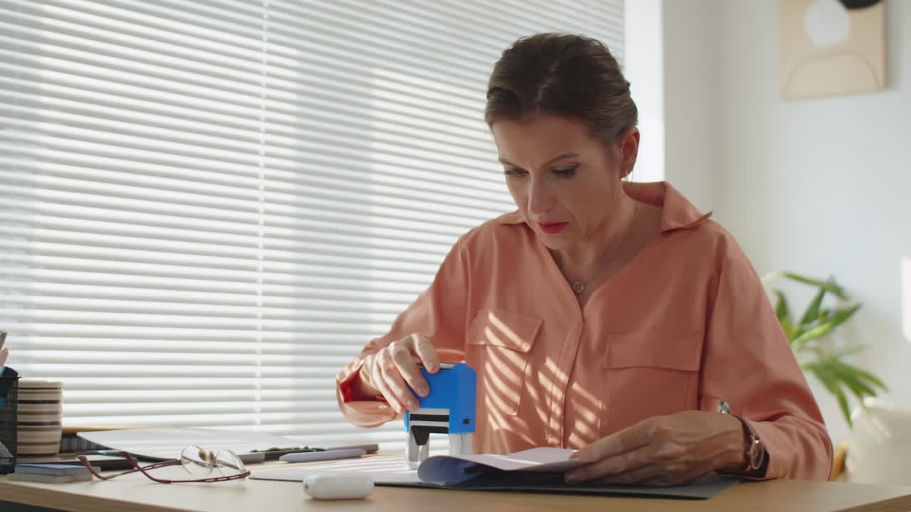 Donna che timbra un documento di lavoro alla scrivania dell'ufficio