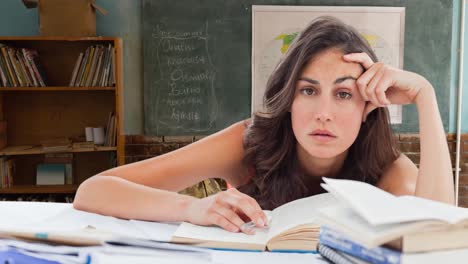 Animation-of-stressed-female-teacher-leaning-on-desk-with-books-over-school-classroom