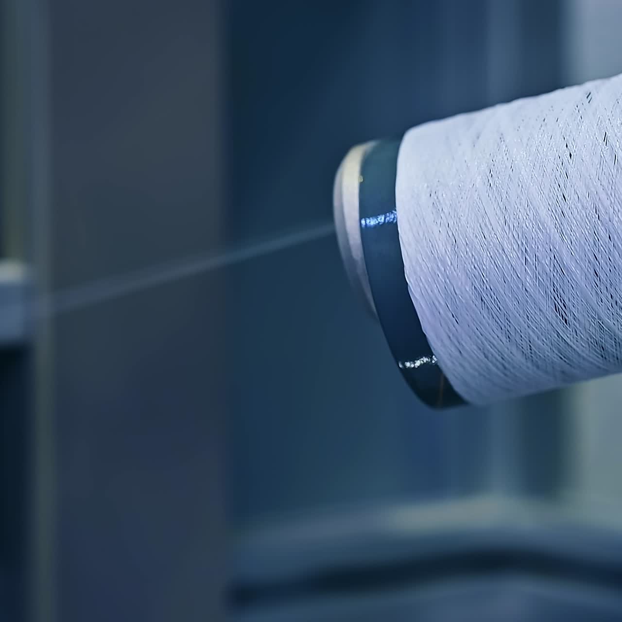 Nylon white thread being unwind from a thick reel. Thread used for sewing the diaper parts at the nappies factory. Close up