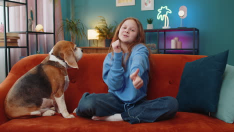 niña mirando con aprobación a la cámara mostrando los pulgares hacia arriba como un signo positivo con un lindo perro beagle