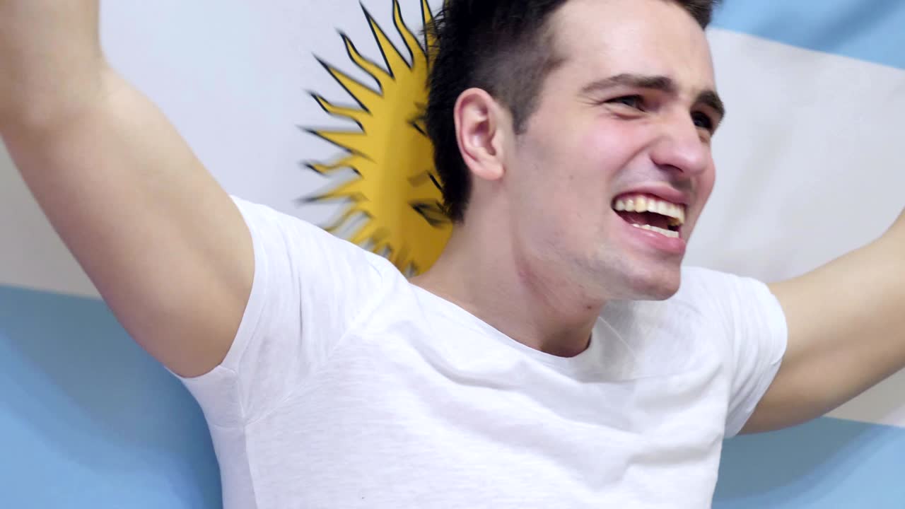 joven argentino celebrando mientras sostiene la bandera de argentina en cámara lenta