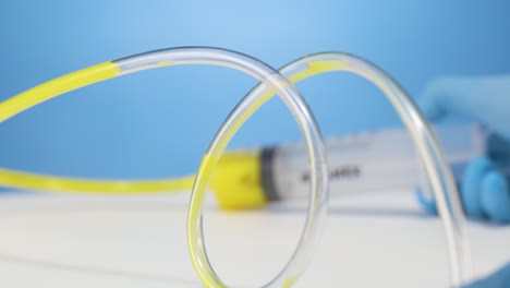Yellow-liquid-flows-through-transparent-tube,-medical-syringe,-studio-shot