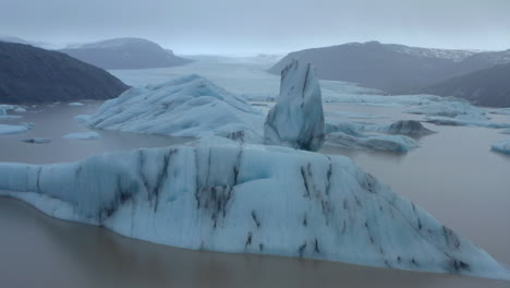 Low-slow-aerial-shot-through-icebergs-towards-a-large-glacier