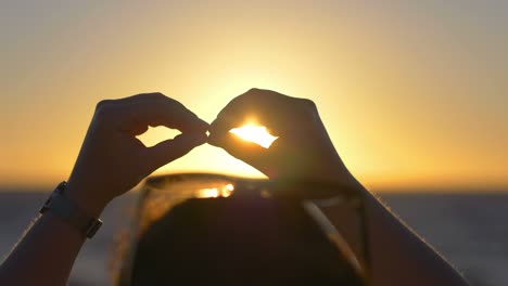 woman makes the sign of infinity with hands at sunset in 4k slow motion 60fps