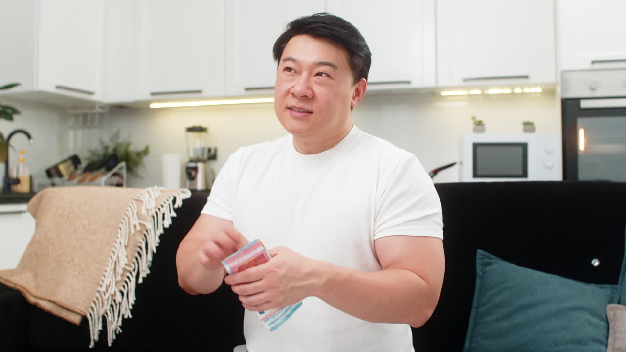 ชายชาวเอเชียนับเงินสดสกุลยูโร ยิ้ม แลกเป็นเครื่องหมายเงินตรา และวางแผนที่จะลงทุน ซื้อ โบนัส เงินเดือน เงินออม