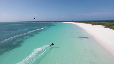 man splash kiteboard on blue water, drone shot crasqui tropical island